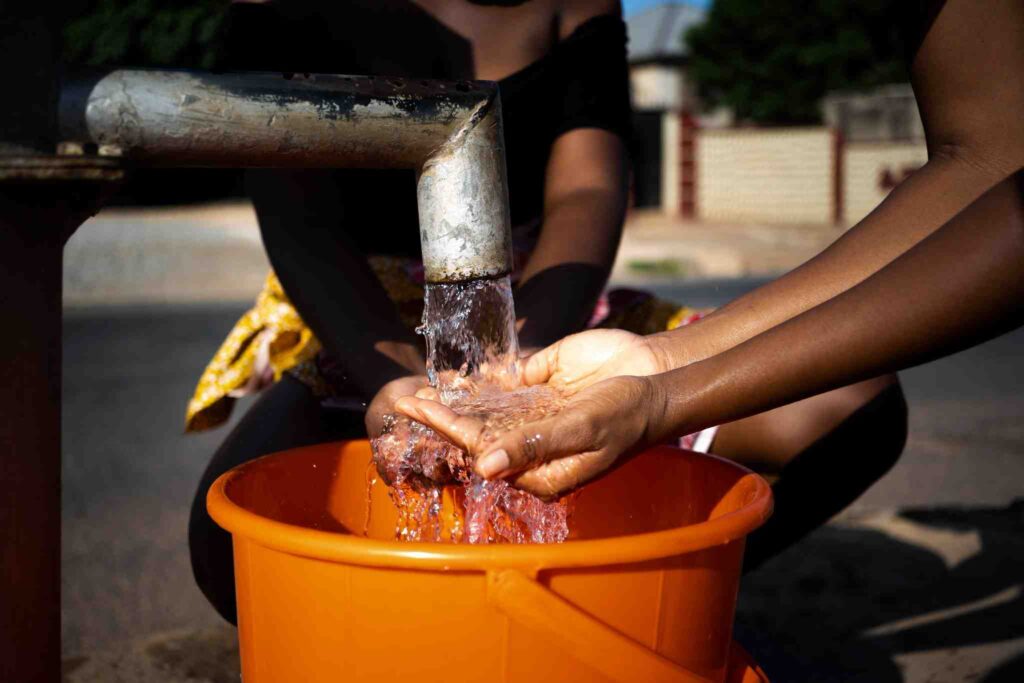 mulher-africana-servindo-agua-em-um-recipiente-ao-ar-livre
